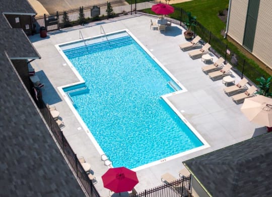 a swimming pool in a backyard with umbrellas and chairs