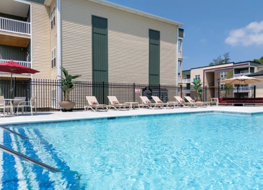 a swimming pool with chairs and a building in the background