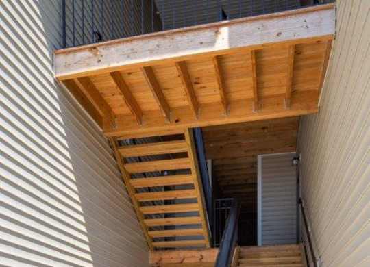 A wooden staircase with a metal railing leading to a balcony.
