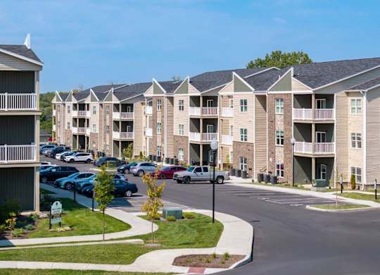 A sunny day at a residential apartment complex with cars parked in the parking lot.