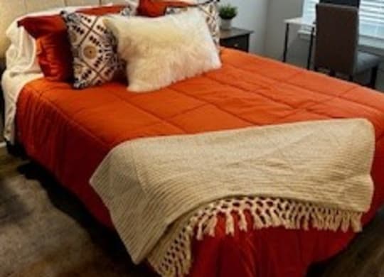 a bedroom with an orange and white bed