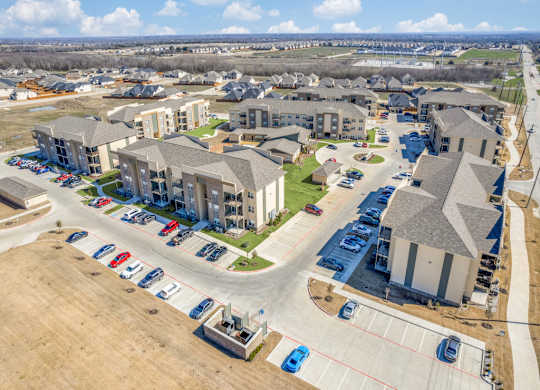 A large apartment complex with a parking lot in front.