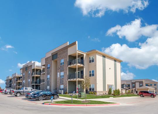 A large apartment complex with cars parked in front.
