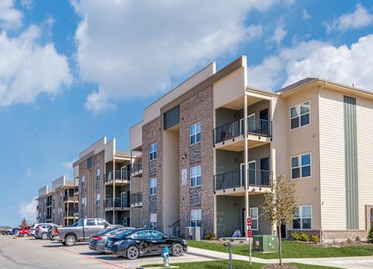A row of modern apartment buildings with cars parked in front.