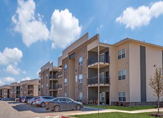 Apartment building with cars parked in front.
