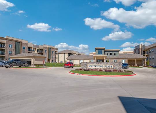A parking lot in front of a building named Whitewing Flats.