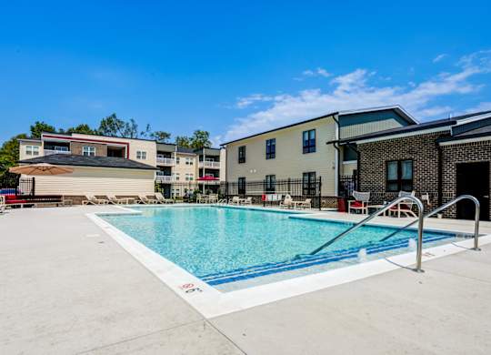 A swimming pool in front of a building with a blue sky in the background.