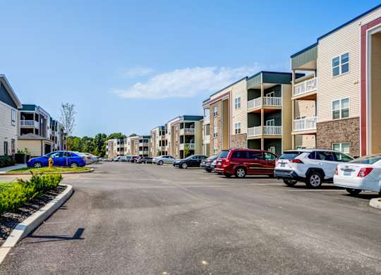 A parking lot with cars and apartment buildings in the background.