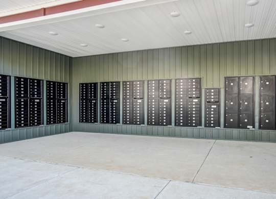 A wall of black lockers in a room with a concrete floor.
