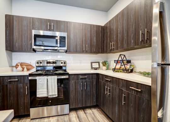 A modern kitchen with dark wood cabinets and stainless steel appliances.