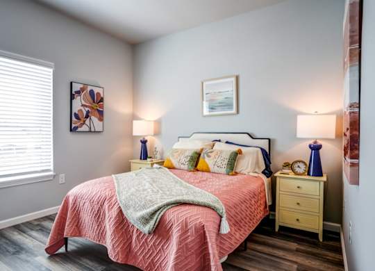 A bedroom with a bed, nightstands, and a window.
