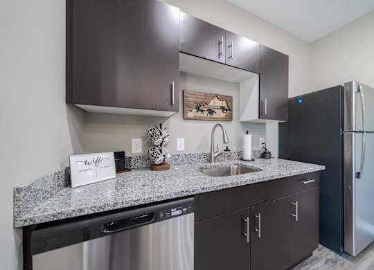 A kitchen with dark brown cabinets and a black refrigerator.