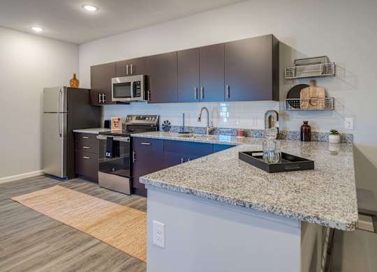 A kitchen with a granite counter top and stainless steel appliances.