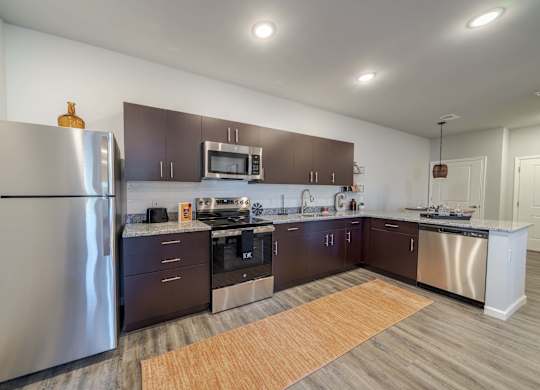 A modern kitchen with dark brown cabinets and stainless steel appliances.