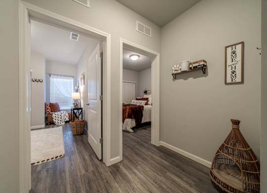 A hallway with a wooden floor and a wall shelf with a sign that says "Home Sweet Home".