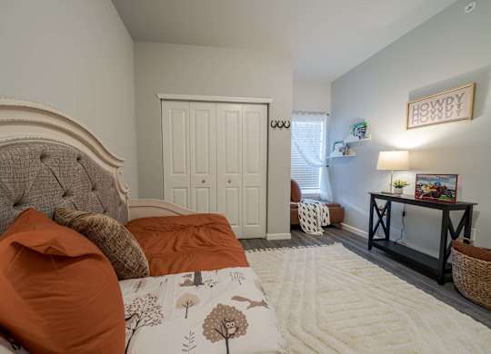 A bedroom with a large bed and a small table with a lamp.