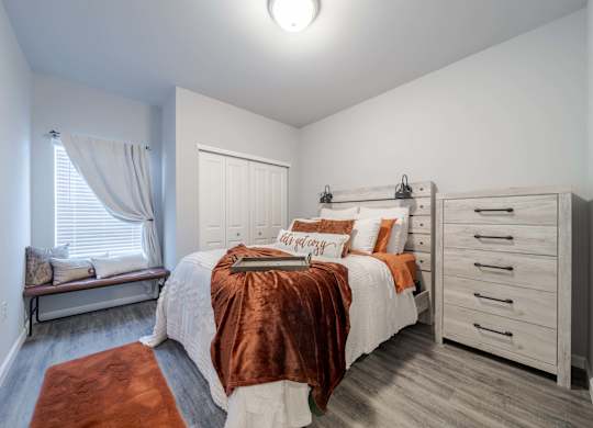 A bedroom with a bed, dresser, and window.