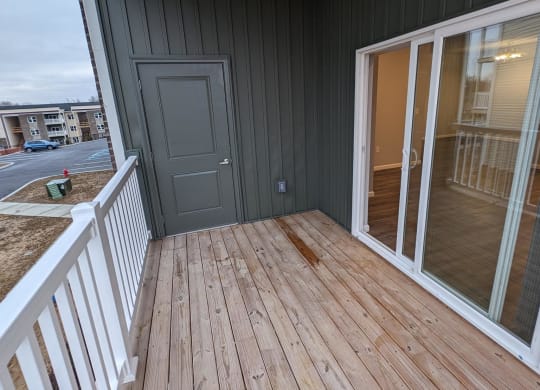a porch with a wooden deck and a gray door