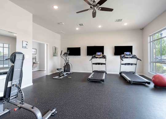 A spacious home gym with a treadmill, exercise bike, and a weight bench.