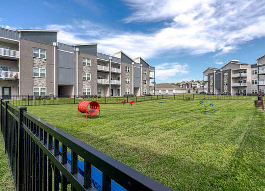 Apartment complex with a green lawn and playground equipment.
