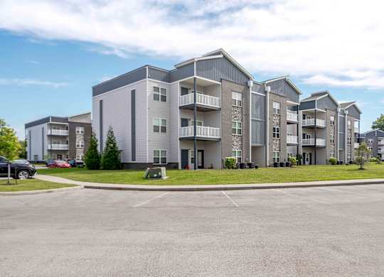 A large apartment complex with multiple buildings and a parking lot in front.