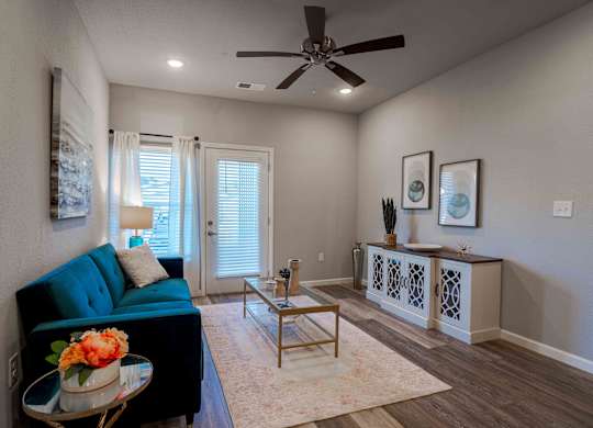 a living room with a blue couch and a ceiling fan
