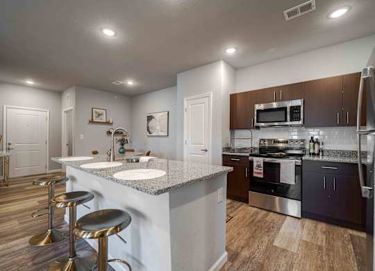 a kitchen with stainless steel appliances and a counter with stools