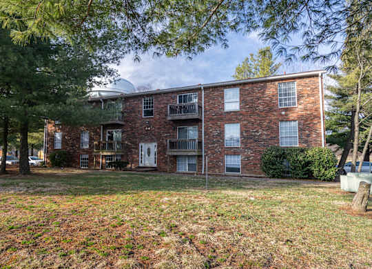 A brick apartment building with a green lawn in front.