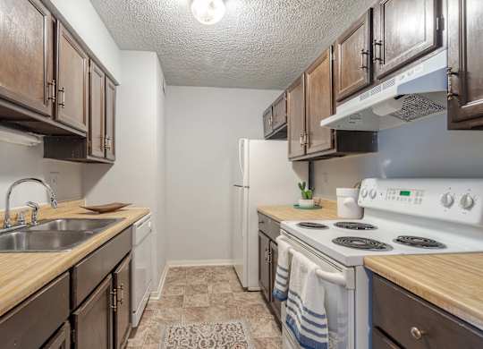 A kitchen with wooden cabinets and a white stove top oven.