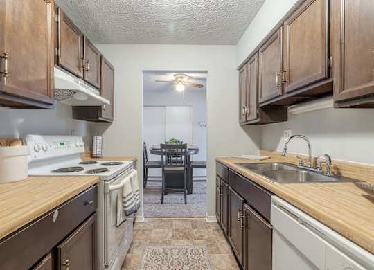 A kitchen with wooden cabinets and a white stove top oven.