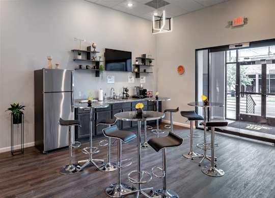 a kitchen area with bar stools and a counter with a refrigerator