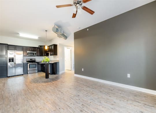 an empty kitchen and living room with a ceiling fan
