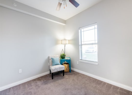 a living room with a chair and a ceiling fan