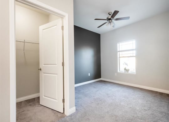 an empty bedroom with a closet and a ceiling fan