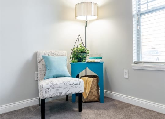 a living room with a chair and a table with a lamp