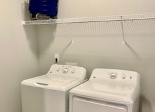 two washers and dryers in a room with a white wall