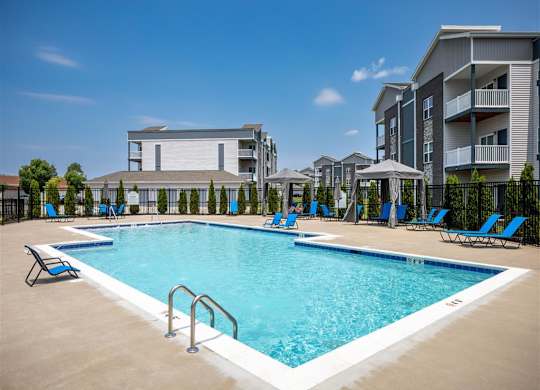 a resort style pool with blue chairs and a building in the background