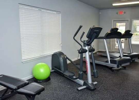 a gym with exercise equipment and a green ball