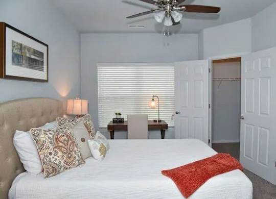 a bedroom with a large white bed and a ceiling fan