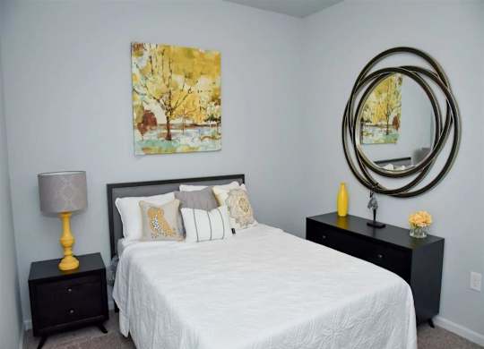 a bedroom with a white bed and a mirror