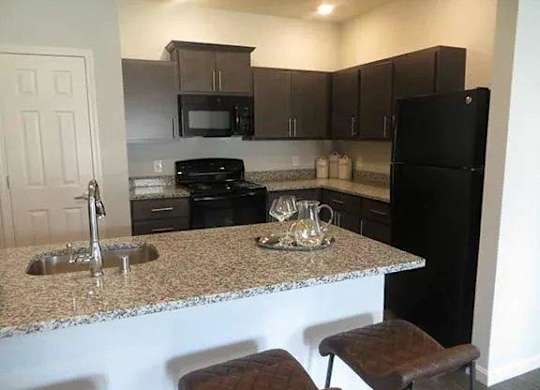 a kitchen with a granite counter top and a black refrigerator