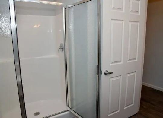 a bathroom with a shower and a white door