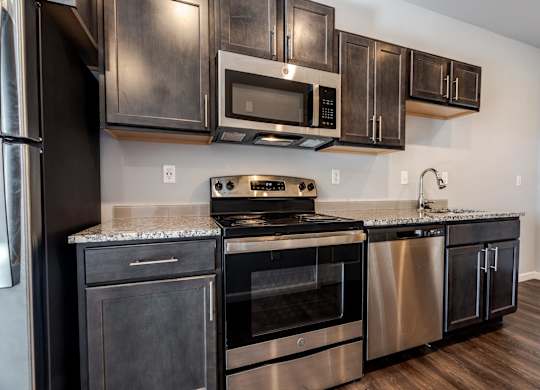 A modern kitchen with dark wood cabinets and stainless steel appliances.