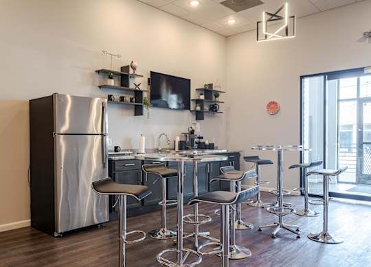 A modern kitchen with a large stainless steel refrigerator and matching bar stools.