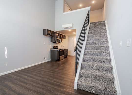 A staircase with a carpeted runner leads up to a second floor landing.