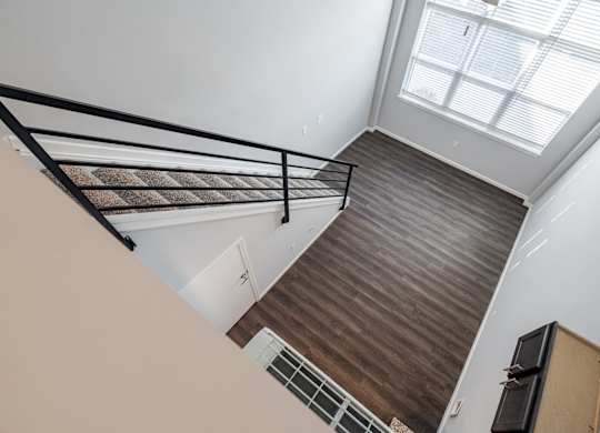 A staircase with a metal railing and wooden steps leading to a skylight.