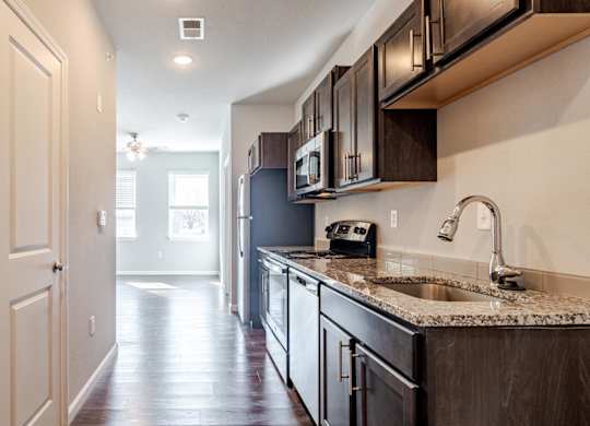 A kitchen with dark wood cabinets and a granite countertop.