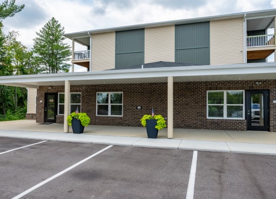 the front of a brick apartment building with a covered parking lot
