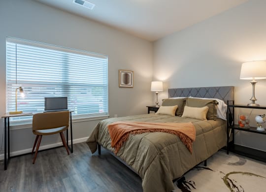 a bedroom with a bed and a desk with a laptop