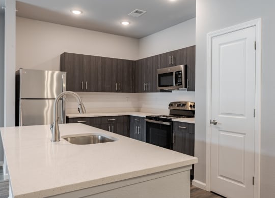 a kitchen with a white counter top and a stainless steel refrigerator
